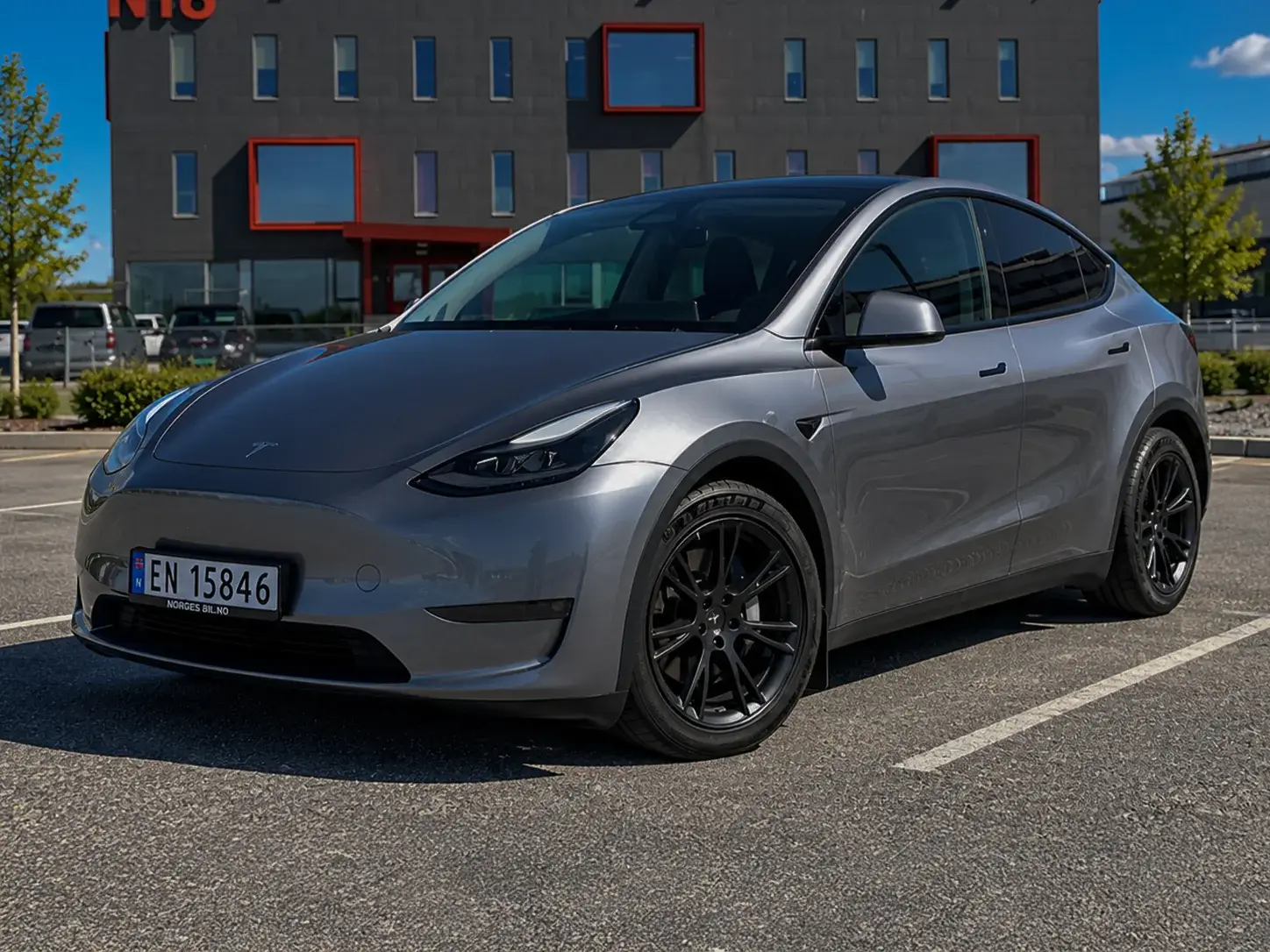 Skolebilen, en grå Tesla Model Y, parkert på en parkeringsplass.